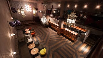 Um interior moderno com área de bar, assentos com mesas redondas e iluminação decorativa.