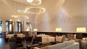 Un hall d’entrée spacieux doté de plusieurs coins salon, d’une cheminée et d’un éclairage moderne.
