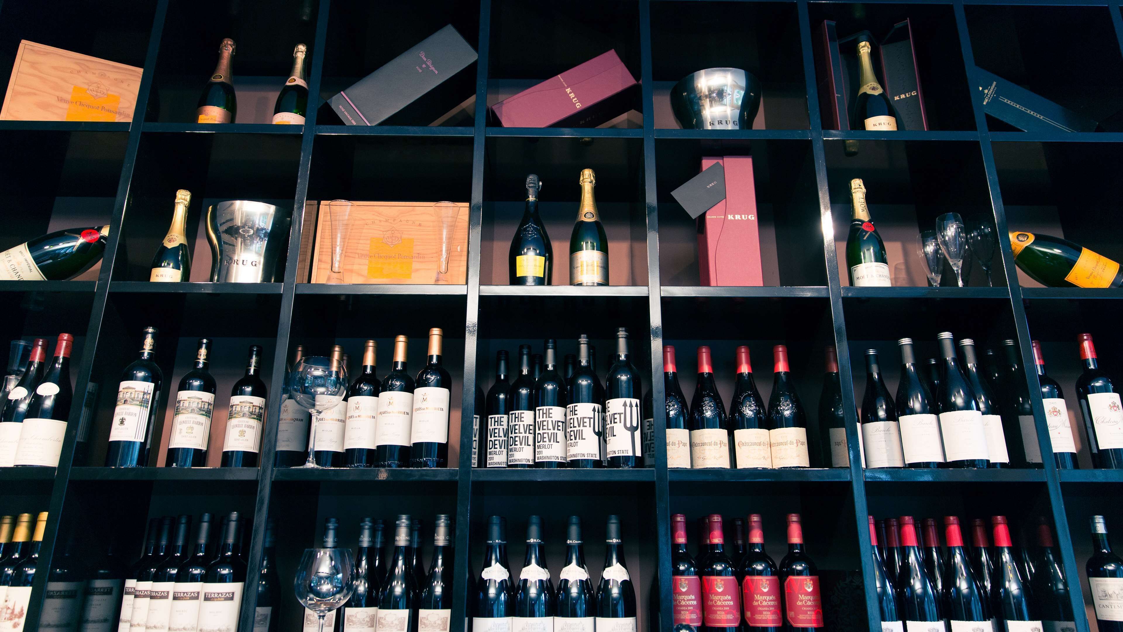 A wine cellar with multiple shelves containing various bottles of wine and champagne.