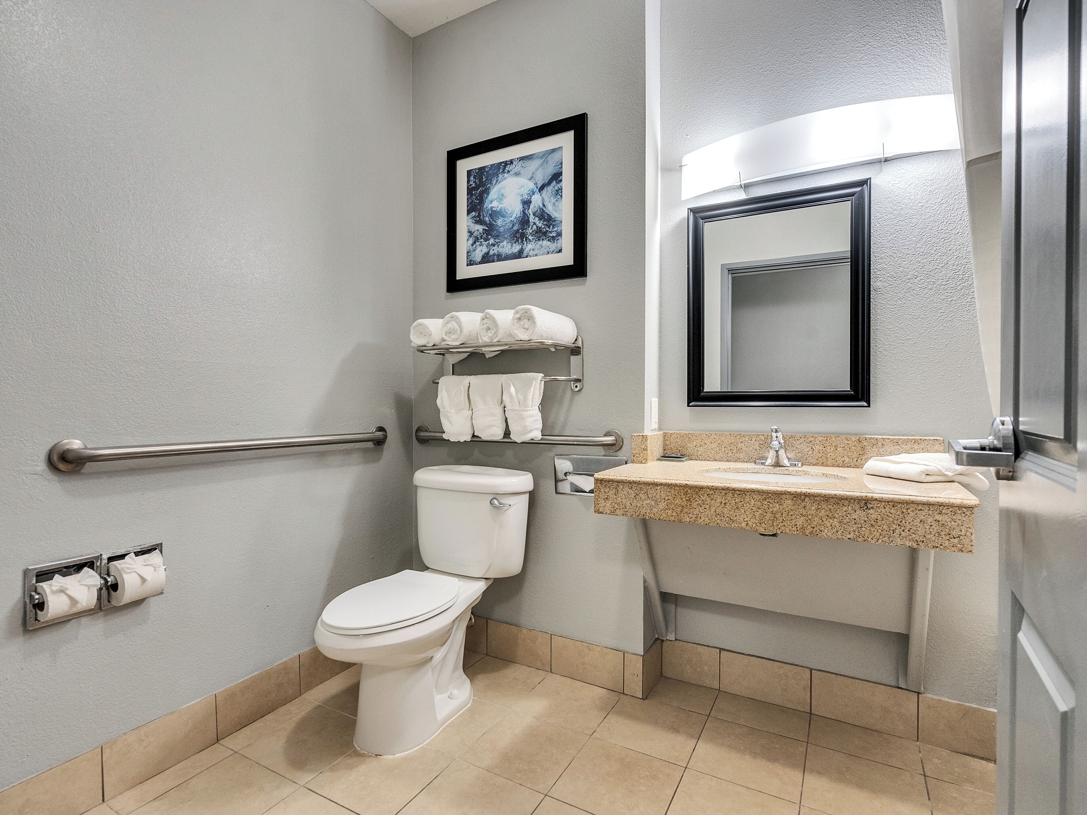 Un baño moderno con inodoro, lavabo, toallero y un cuadro enmarcado en la pared.