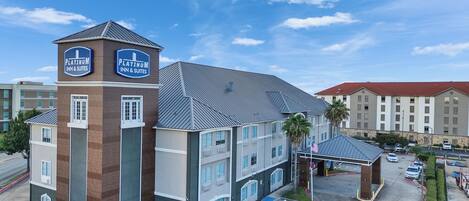 A hotel with a prominent tower, multiple parking spaces, and a clear sky.