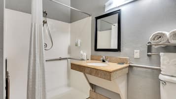 A modern bathroom with a shower, sink, and toilet.