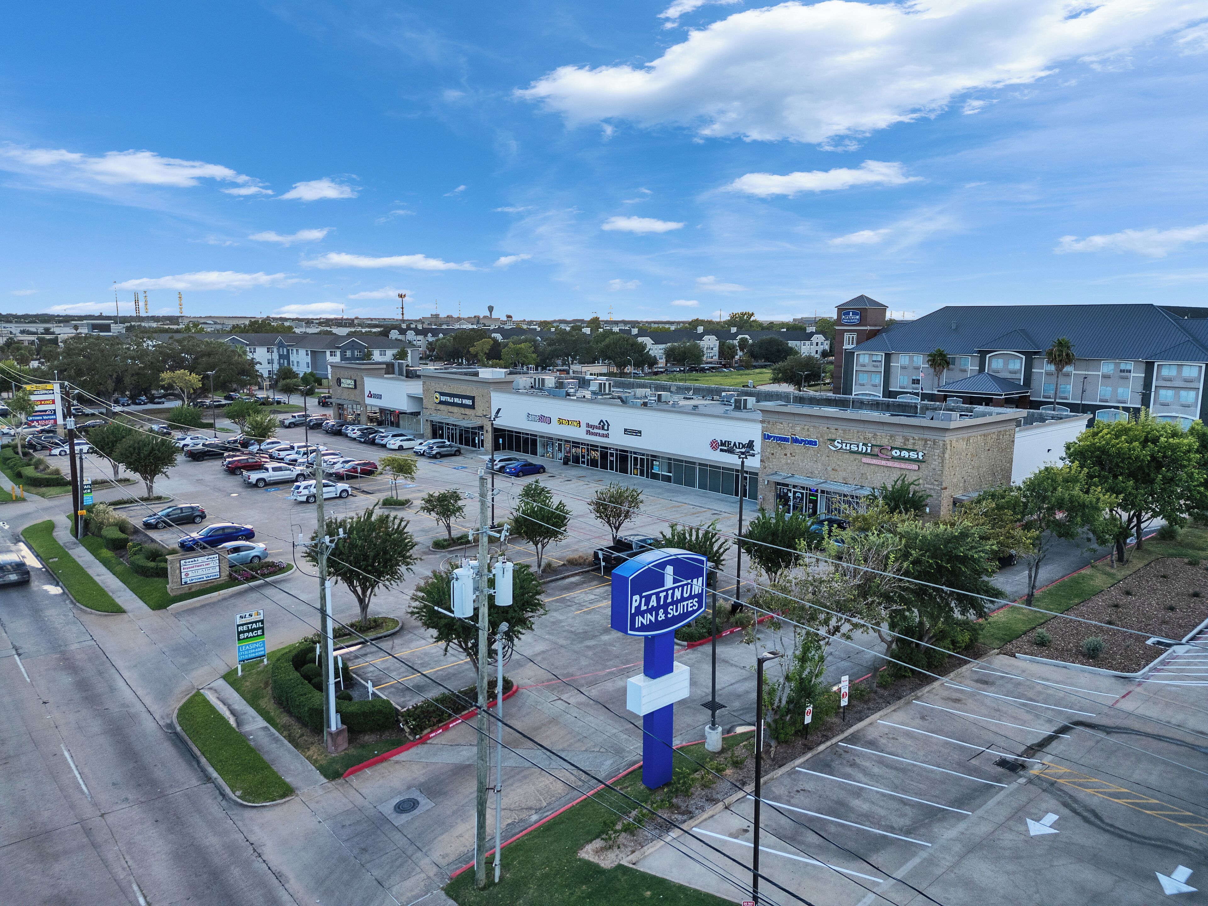Une enseigne « Platinum Inn & Suites », un parking et un centre commercial abritant divers commerces.