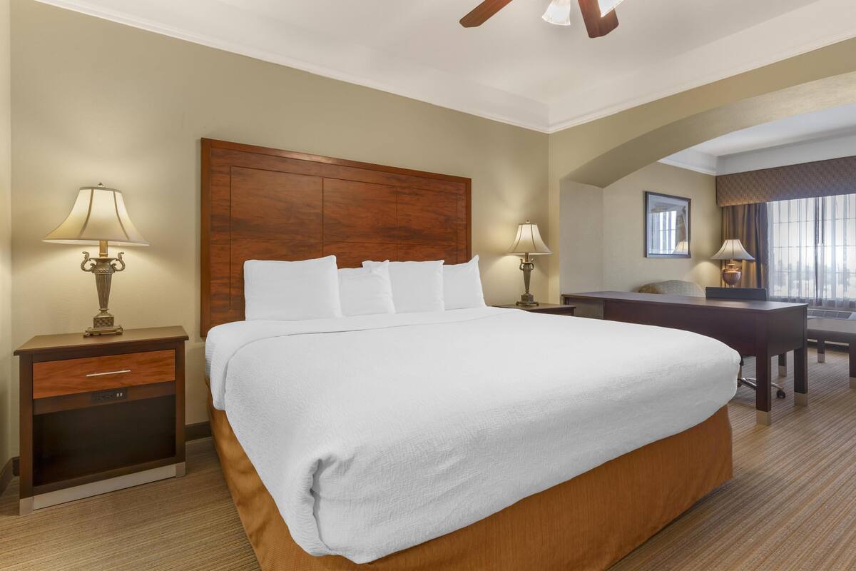 Une chambre d’hôtel avec un grand lit, un bureau, deux lampes et une vue sur la ville par la fenêtre.