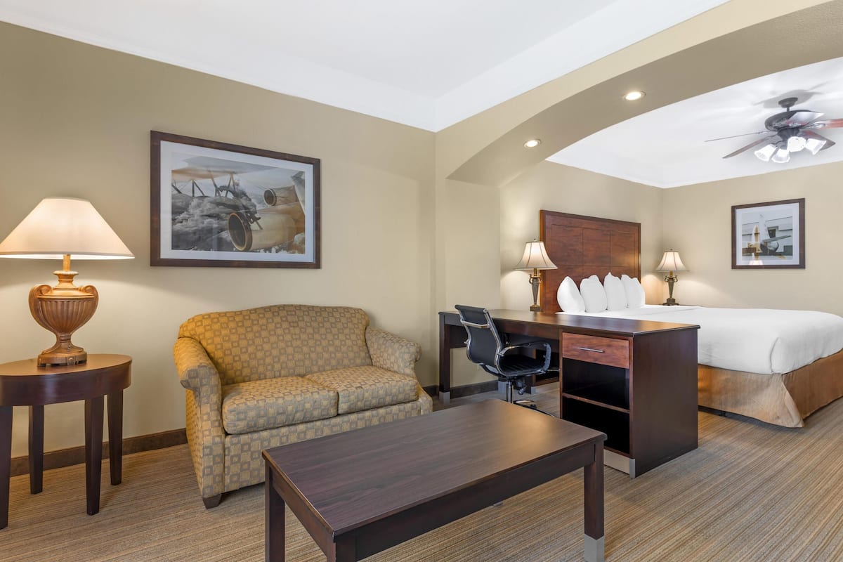 Une chambre d’hôtel équipée d’un canapé, d’un bureau, d’une chaise, d’un lit et d’un ventilateur de plafond.