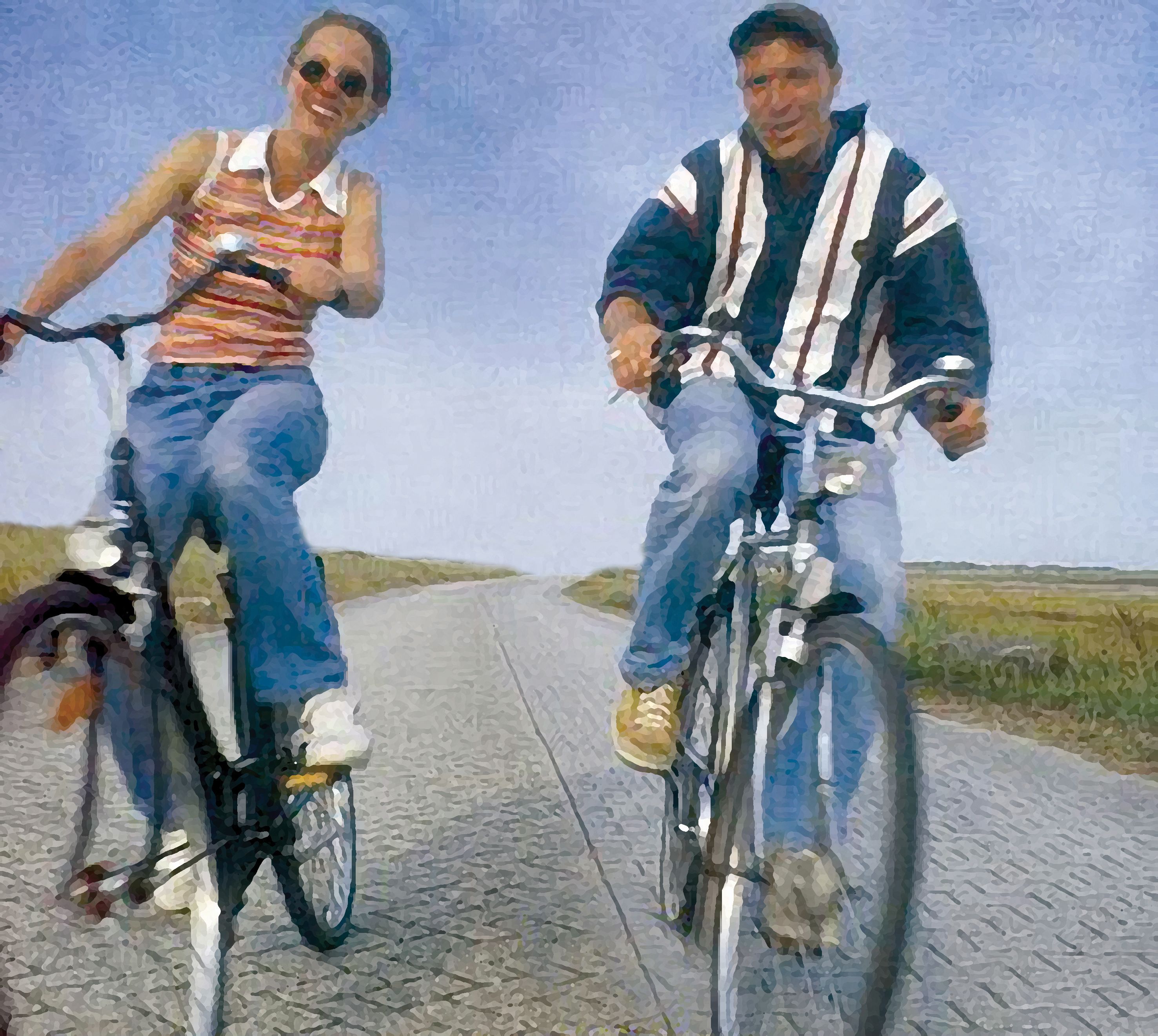Deux personnes font du vélo sur une piste cyclable asphaltée.