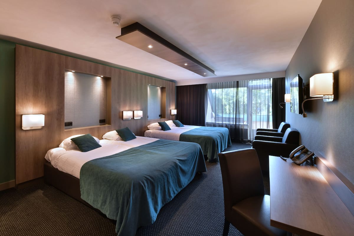 Une chambre d’hôtel avec deux lits, un bureau, une chaise et un téléphone.