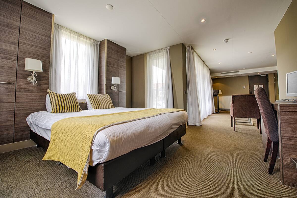 Une chambre d’hôtel avec un grand lit, deux tables de chevet, un bureau et une chaise.