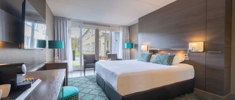 Una habitación de hotel moderna con una cama grande, un escritorio con una silla, un televisor y una ventana con cortinas.