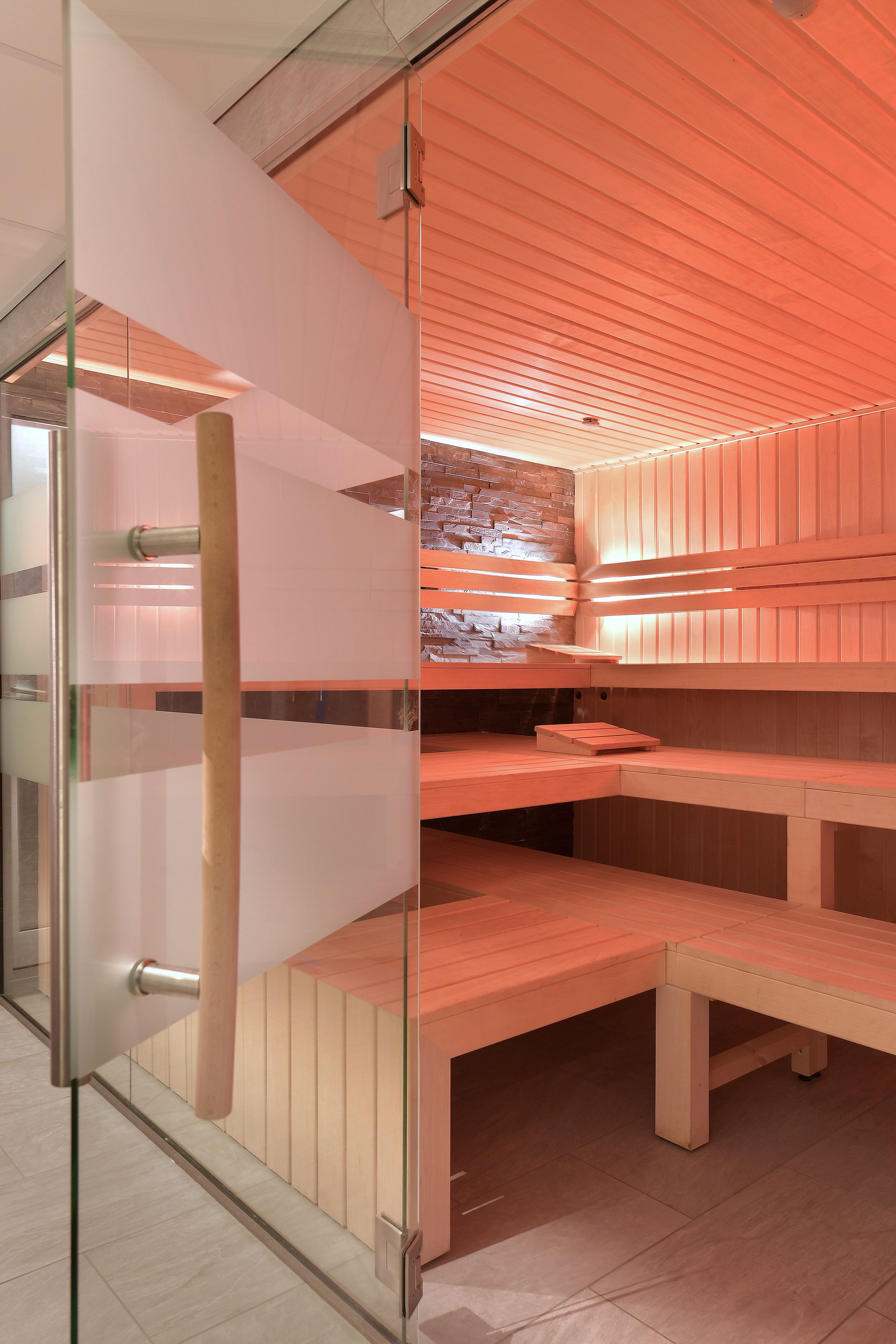 Een sauna met houten banken en een glazen scheiding.