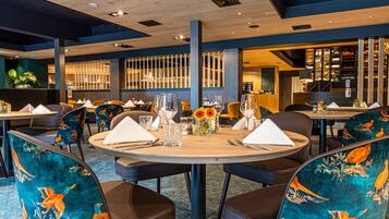 Un restaurante con mesas redondas, sillas de tapicería colorida y una decoración de estilo moderno.