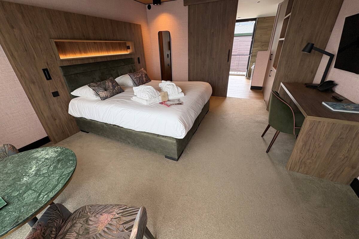 Une chambre d’hôtel moderne avec un grand lit, un bureau, une chaise et une petite table.