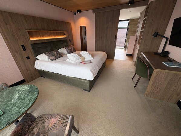 A modern hotel room with a large bed, a desk, a chair, and a small table. - Van der Valk Hotel Gilze - Tilburg (Gilze)