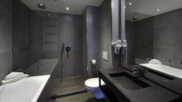 Un baño moderno con bañera, inodoro y zona de ducha.