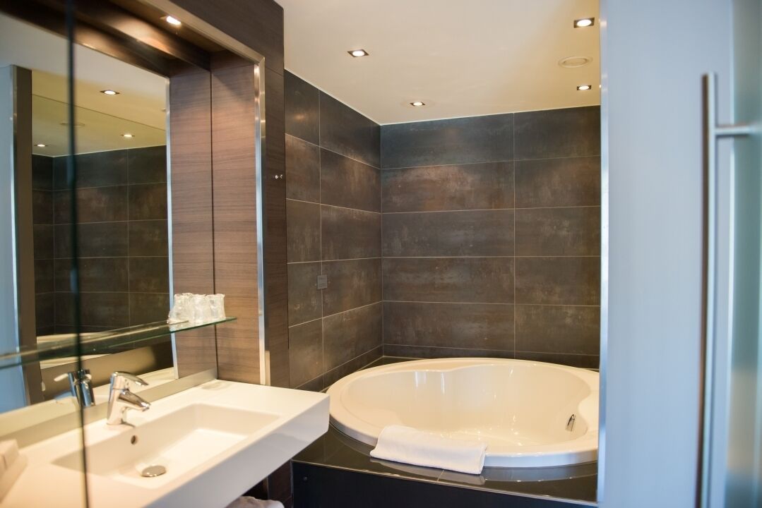 Een moderne badkamer met een groot bad, een wastafel en een glazen plank.