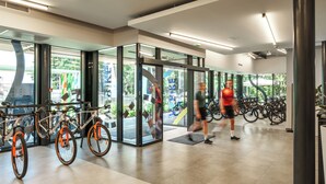 Ett modernt träningsområde inomhus med motionscyklar, glasdörrar och utsikt över den omgivande naturen.