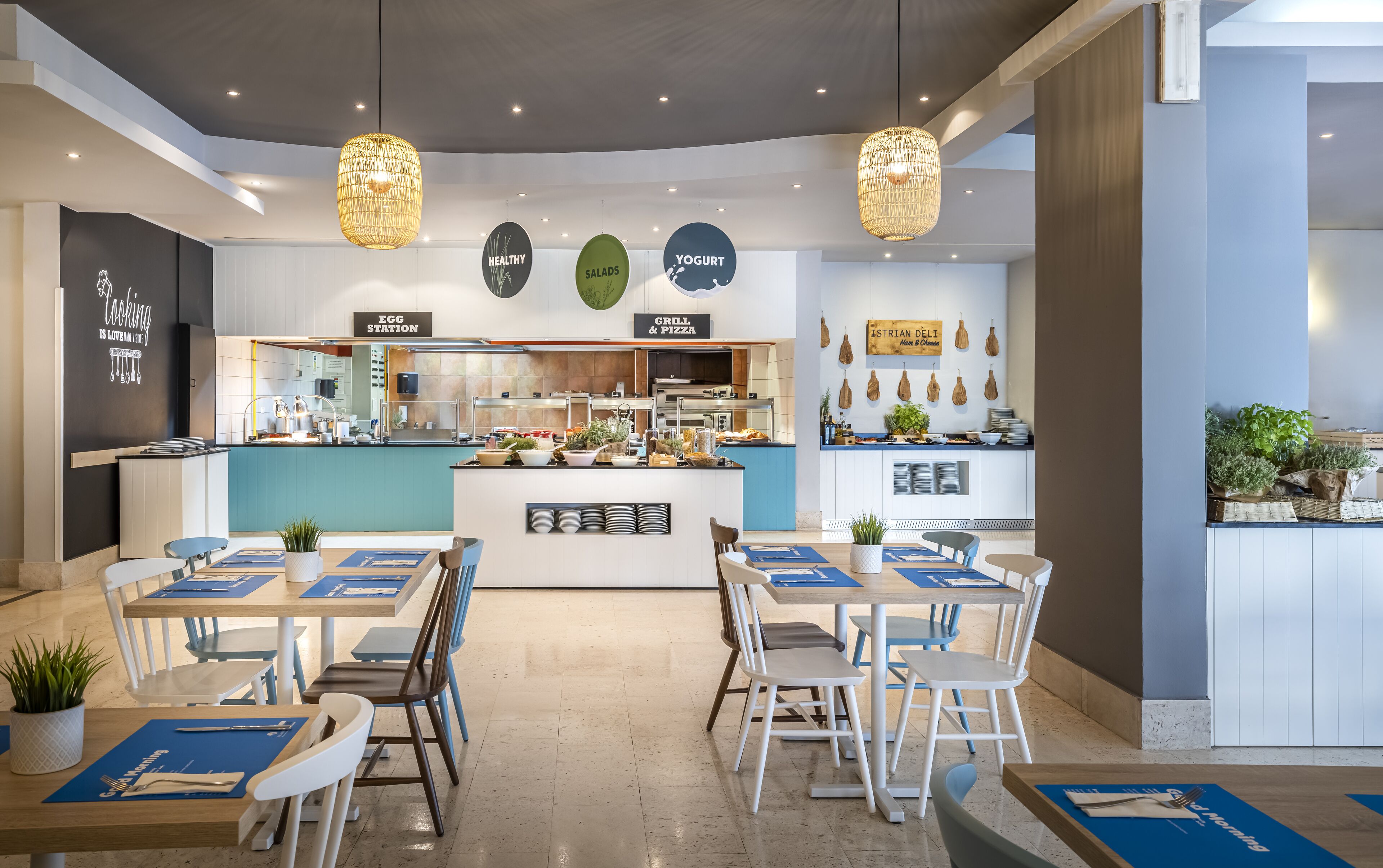 A modern restaurant with a central counter, multiple seating areas, and hanging plants.