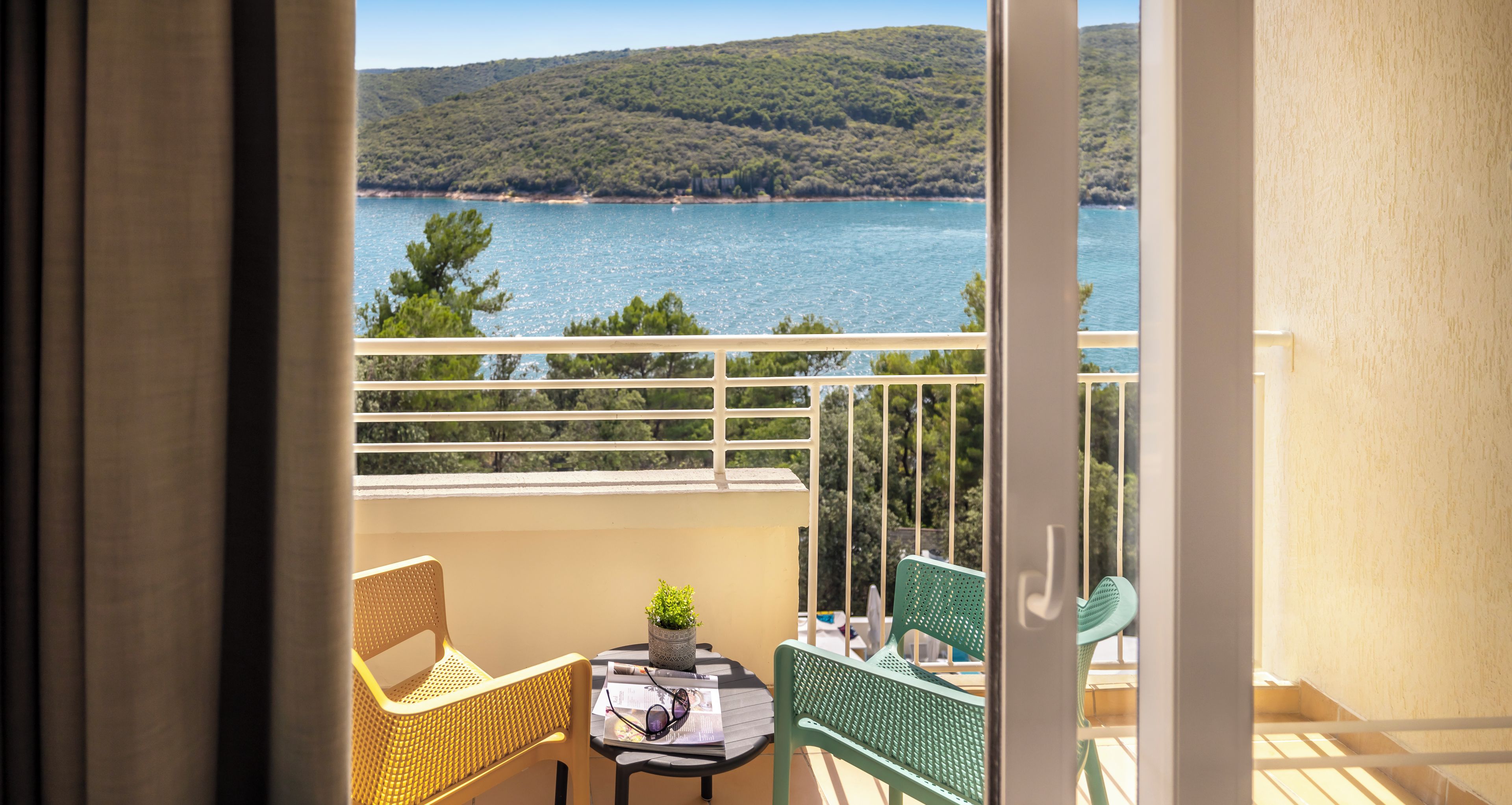 A balcony with wicker chairs, a small table, and a potted plant.