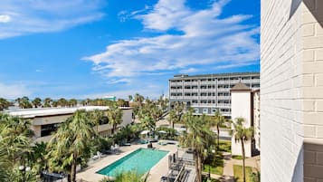 A hotel with a pool, palm trees, and a view of the ocean.