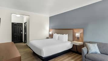 A hotel room with a bed, bedside tables, a desk, and a sofa.