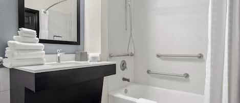 A modern bathroom with a sink, mirror, and bathtub.