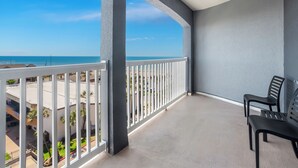 Ein Balkon mit Blick auf das Meer, weißen Geländern und zwei schwarzen Stühlen.