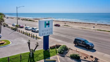 Eine Autobahn mit einem Schild für ein Hyatt Select Hotel, einem Strand und einem klaren, blauen Himmel.