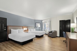 A hotel room with two beds, a desk, a chair, a lamp, and a window with curtains. - Hyatt Select Galveston - Beachfront (Galveston)