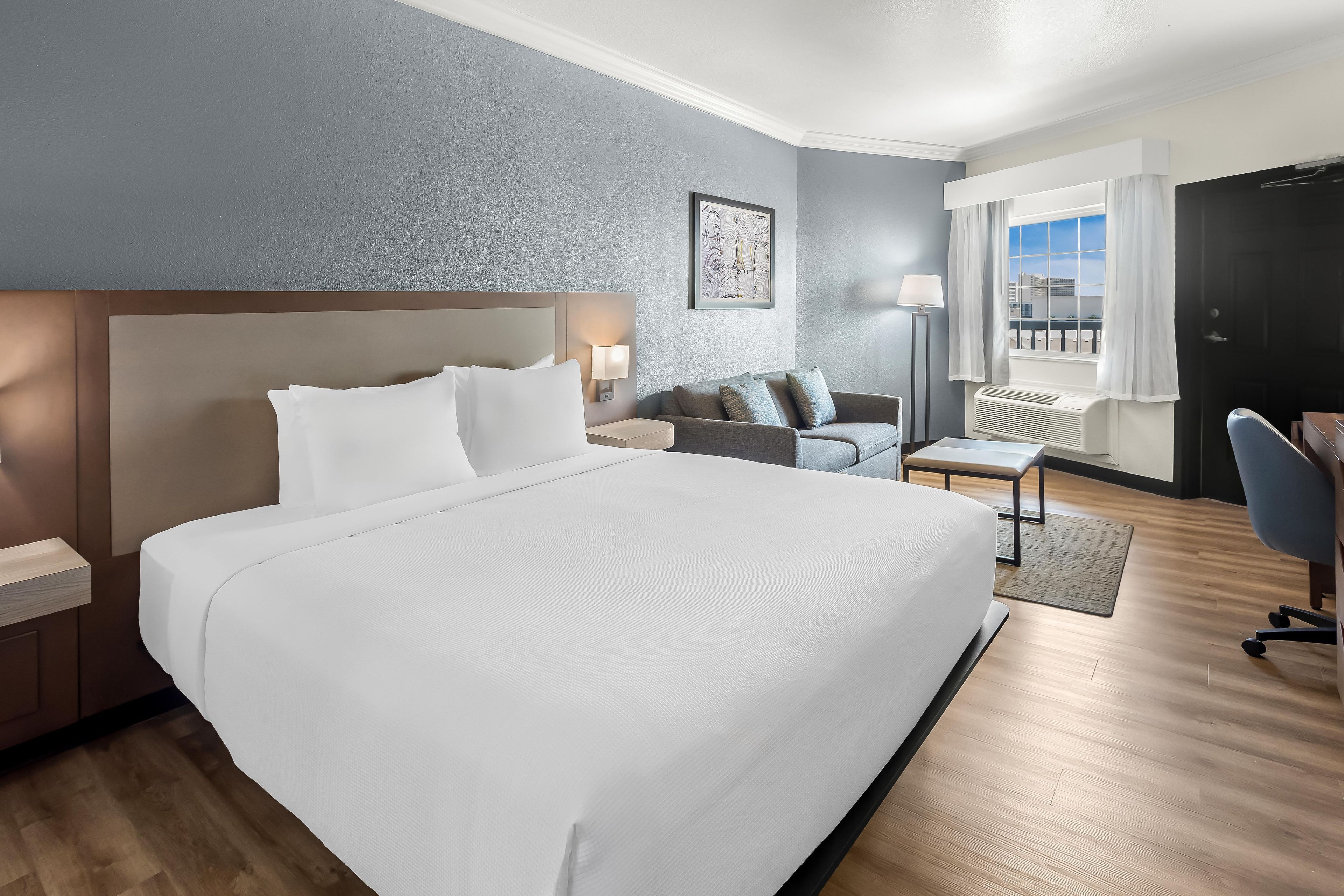 Una habitación de hotel con una cama grande, un sofá, un escritorio y una silla.