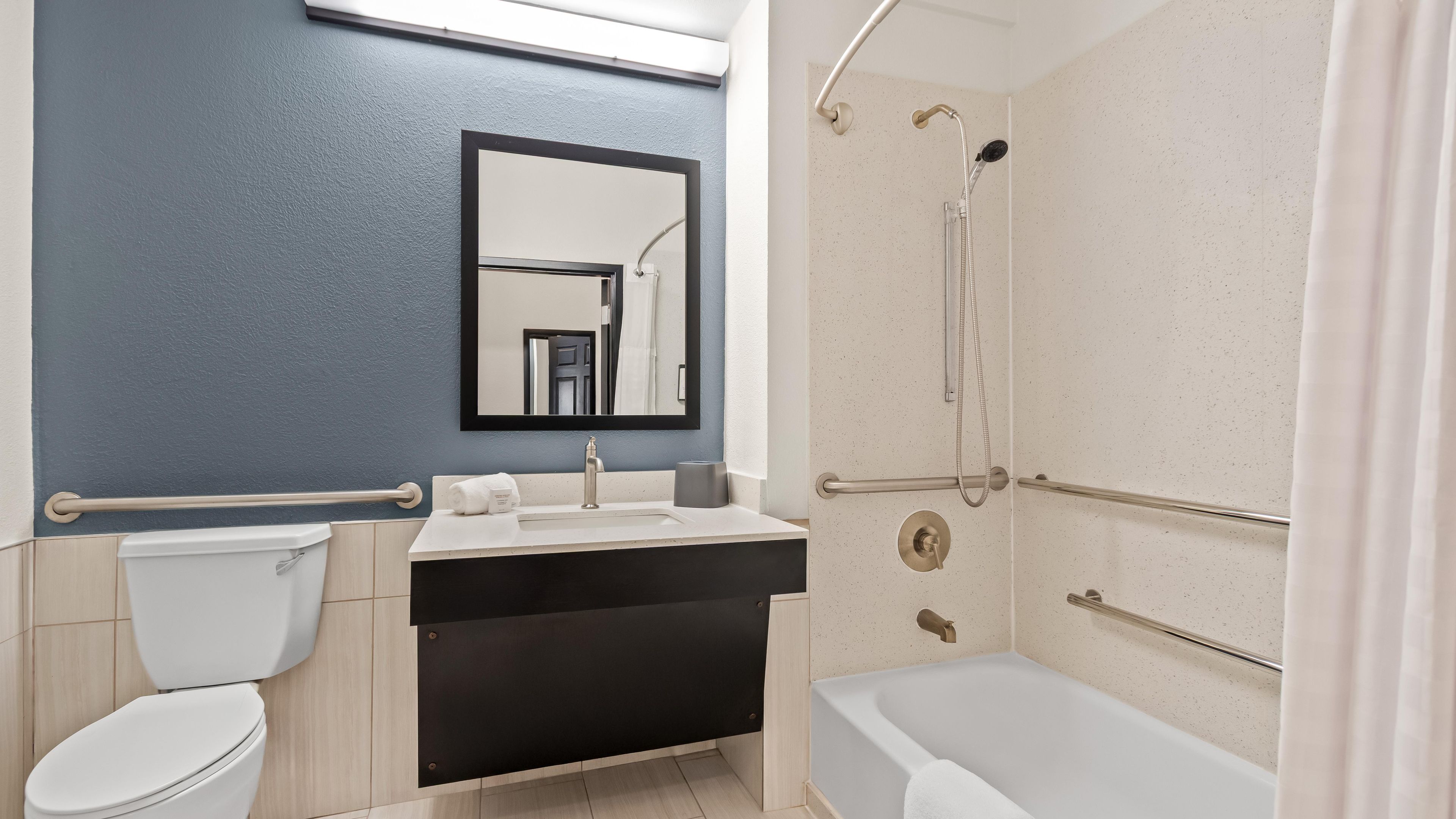 A bathroom with a toilet, sink, mirror, shower, and bathtub.