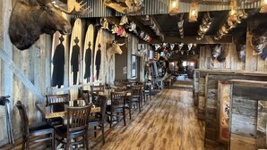 A restaurant interior with wooden walls, mounted animal heads, and rustic decor. - Hyatt Select Galveston - Beachfront (Galveston)