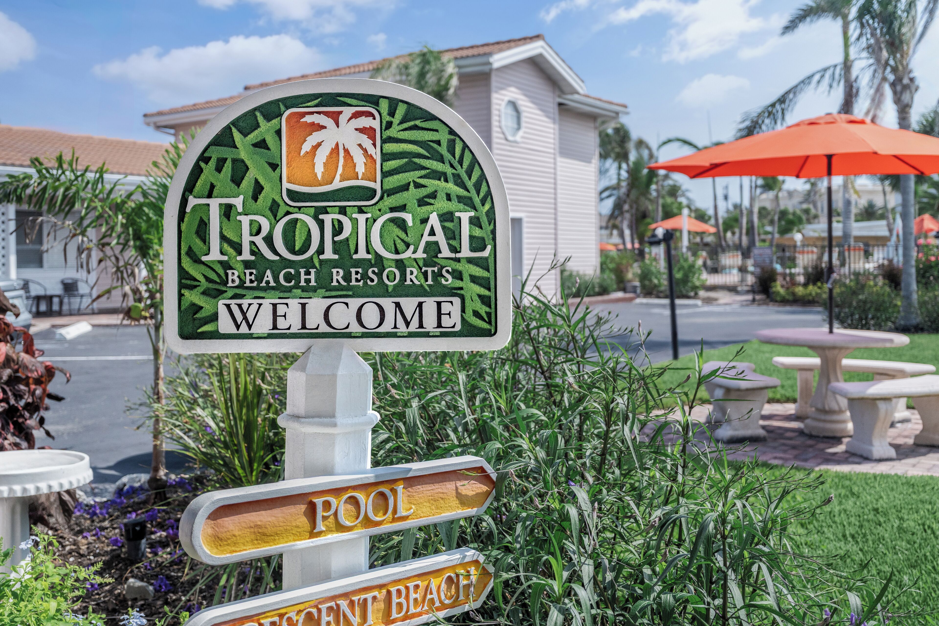 A sign for Tropical Beach Resorts with a palm tree logo, welcoming visitors.
