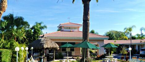 A resort with a pool area, lounge chairs, and a thatched-roof building.