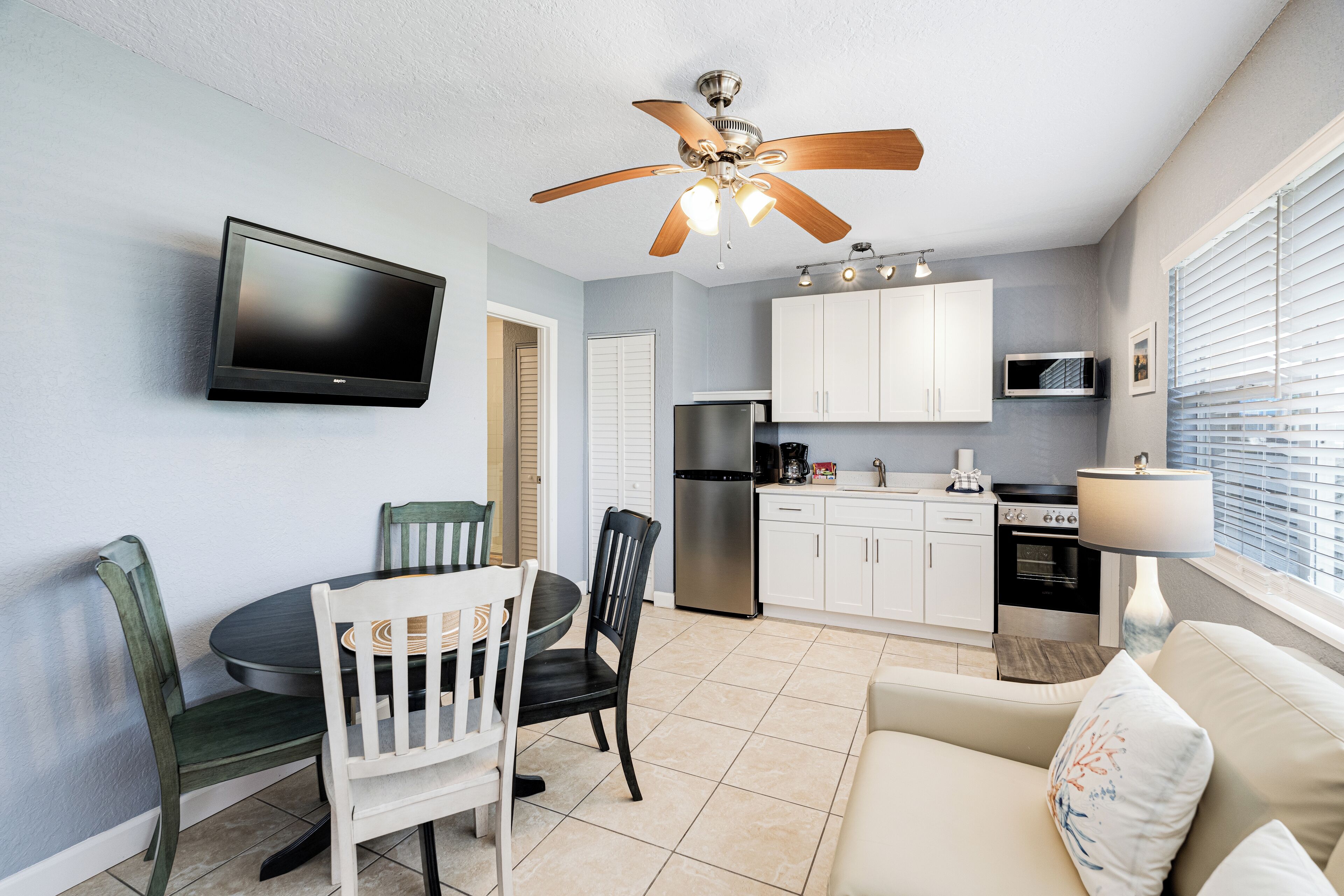 A compact kitchen with white cabinets, a built-in microwave, and a stainless steel refrigerator.