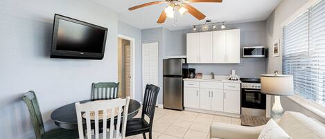 A compact kitchen with white cabinets, a built-in microwave, and a stainless steel refrigerator.