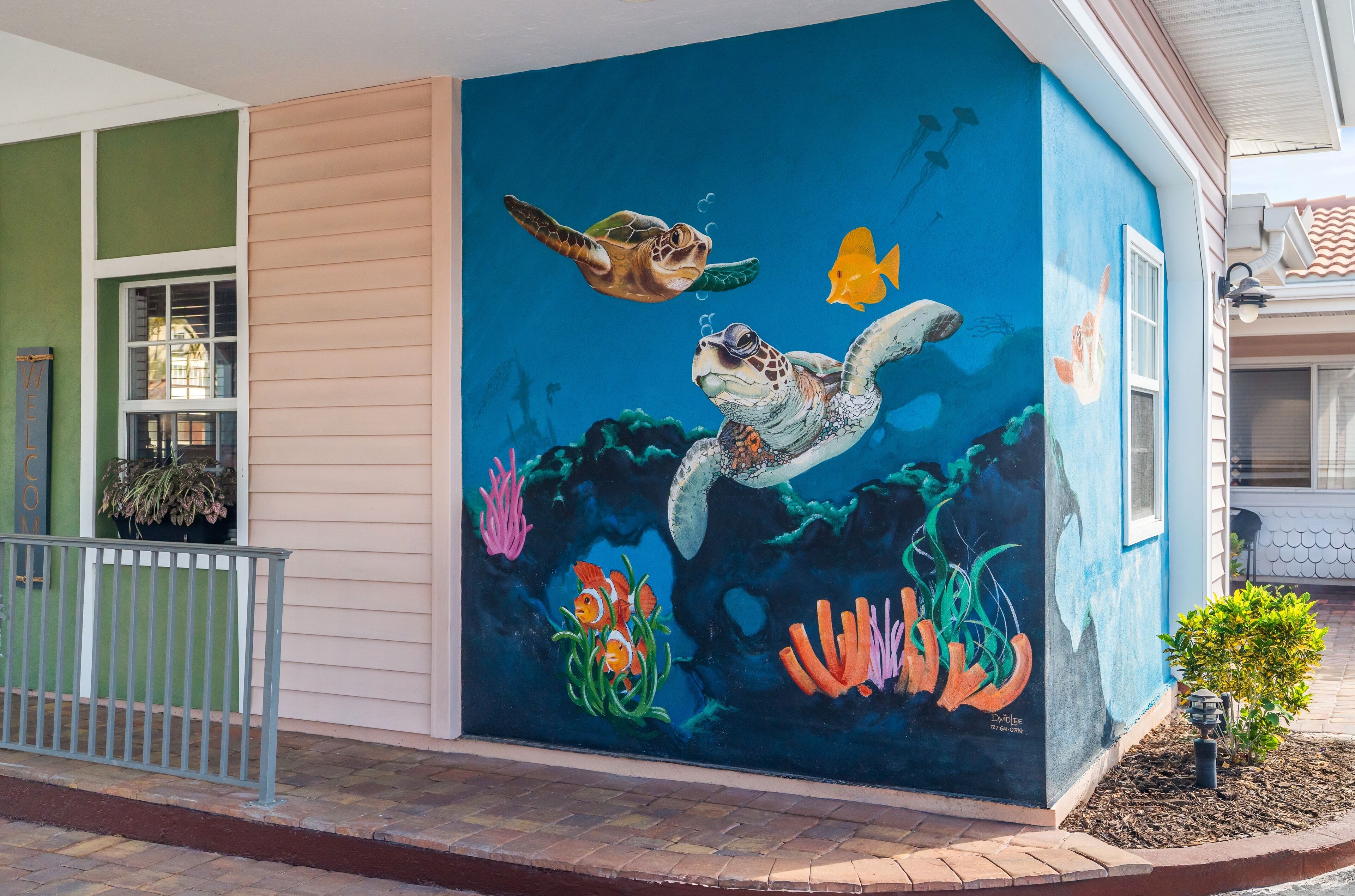 A mural of a turtle swimming with fish and coral on a building's exterior wall.