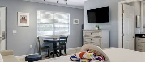 A bedroom with a bed, a desk, a chair, a television, and a wardrobe.