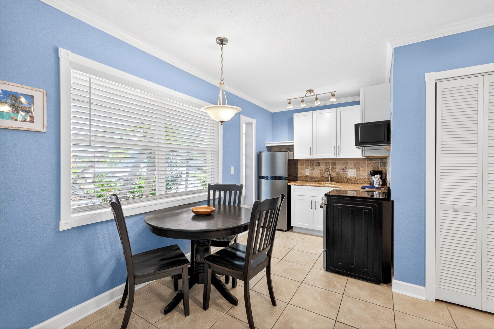 A kitchen with white cabinets, a black countertop, and a dining area with a round table and chairs.
