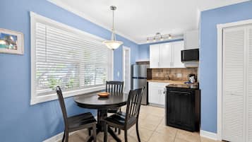 A kitchen with white cabinets, a black countertop, and a dining area with a round table and chairs.
