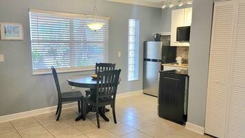 A kitchen with a dining table and chairs, a refrigerator, and a microwave.