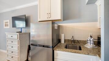 A kitchen with white cabinets, a stainless steel refrigerator, a granite countertop, and a built-in oven.