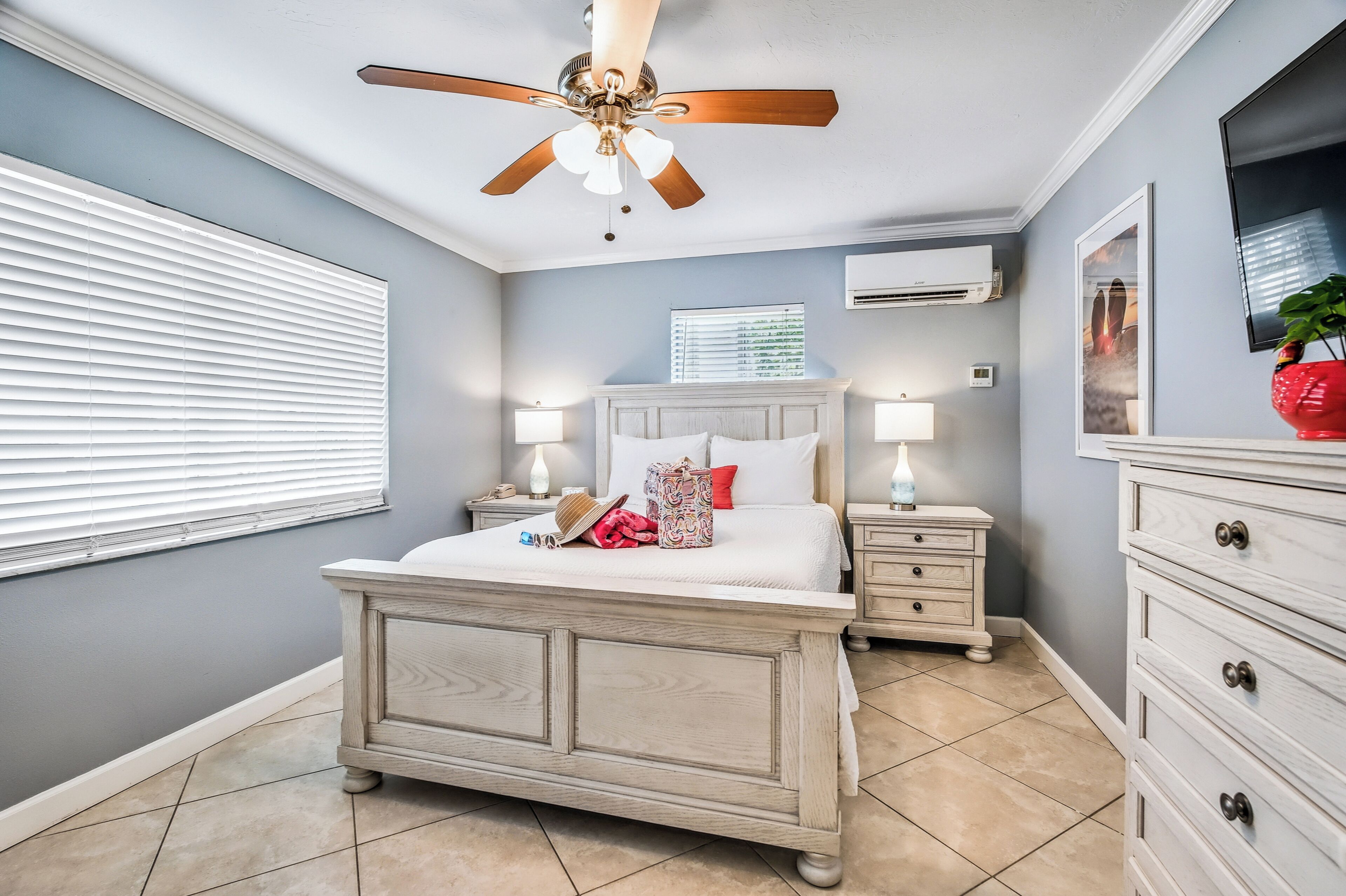 A bedroom with a bed, bedside tables, a ceiling fan, and a TV.