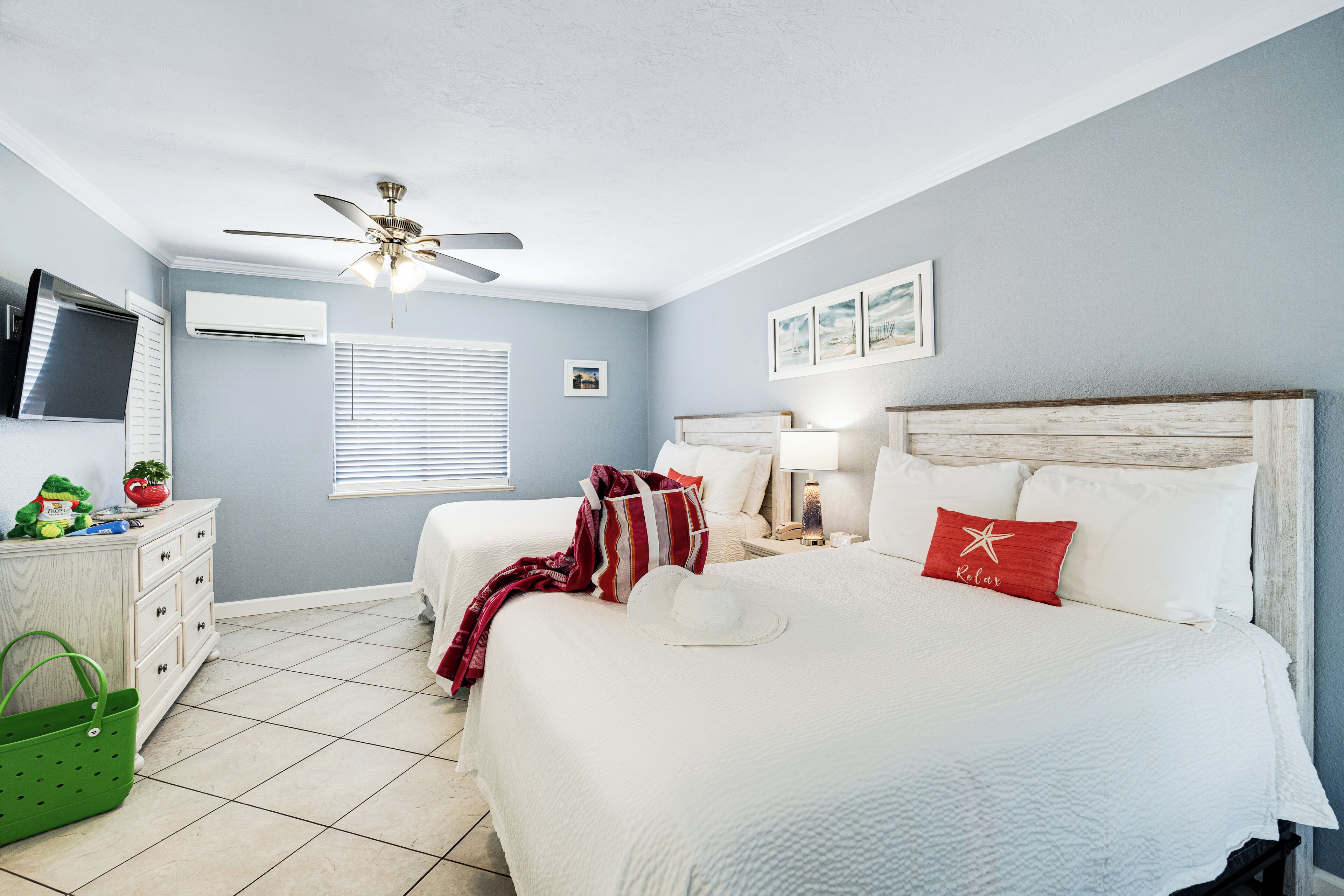 A bedroom with a bed, a ceiling fan, a dresser, and a green bag.