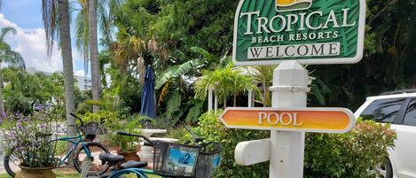 A sign for Tropical Beach Resorts with a pool direction sign.