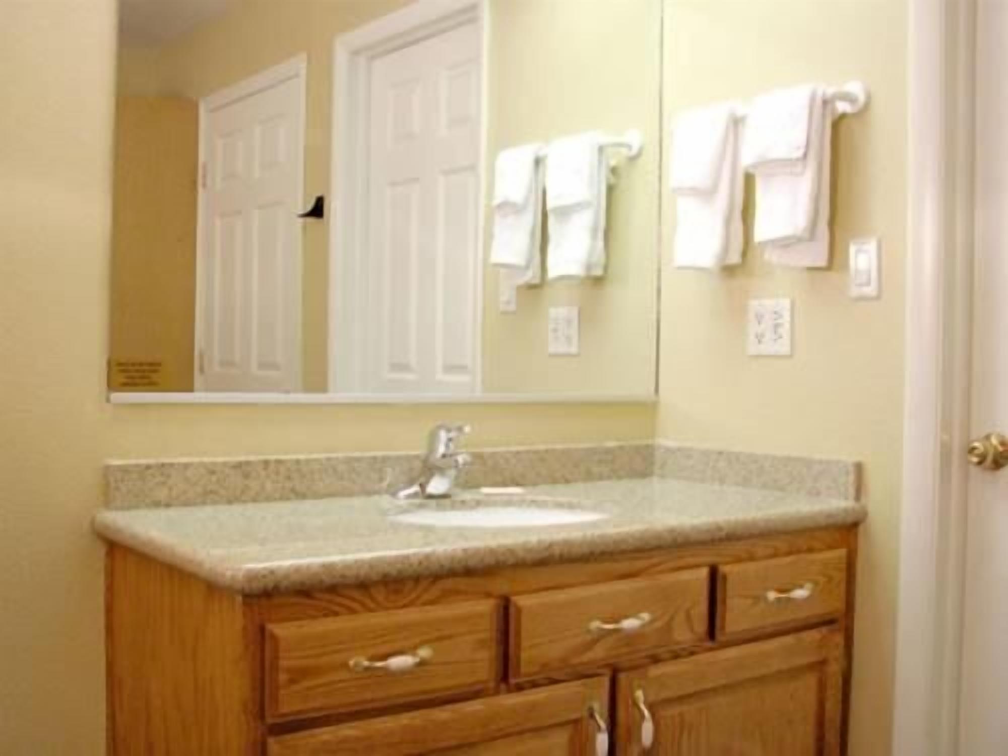 A bathroom with a wooden vanity, a sink, and a mirror.