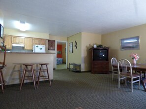 A compact living space with a kitchenette, a dining area, and a television.