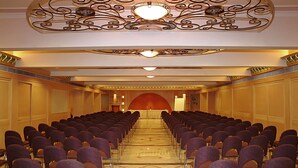 A conference room with rows of chairs, a podium at the front, and ornate ceiling decorations. - Comfort Inn President (Ahmedabad)