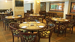 A restaurant with multiple round tables and chairs, each set with plates, cutlery, and napkins. - Comfort Inn President (Ahmedabad)