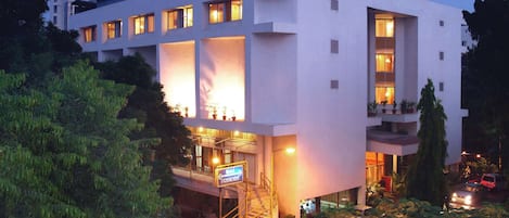 A modern hotel with a flat facade, multiple balconies, and a staircase leading to the entrance.