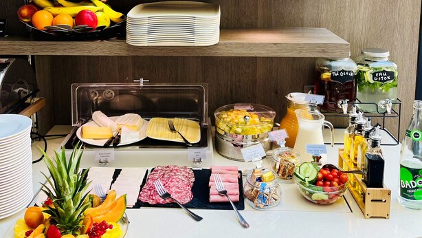 Un buffet proposant une variété de plats, agrémenté d’une plante en pot et d’un distributeur de jus.